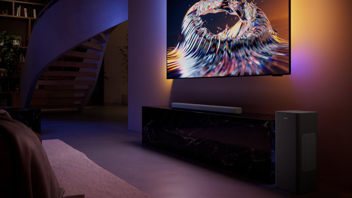 Philips B8301 soundbar sitting in front of a colourful TV screen in a darkened room. The package consists of a main soundbar and a subwoofer.