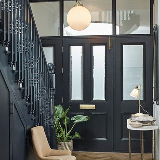 Foyer with a black painted staircase & front door with a round pendant light