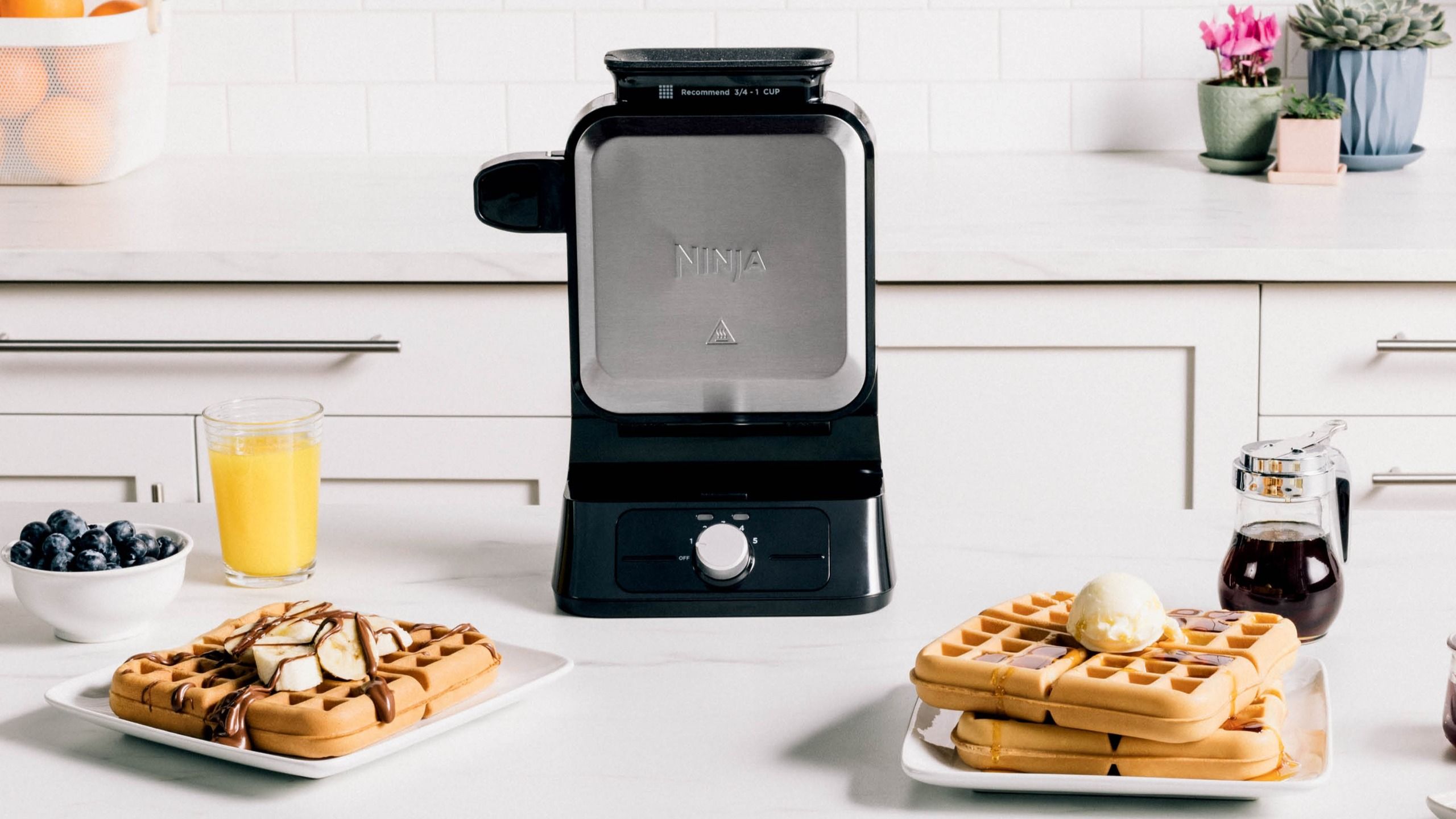 Ninja Belgian Waffle Maker closed, beside plates of waffles