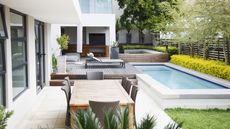 Modern patio with dining table and loungers next to swimming pool