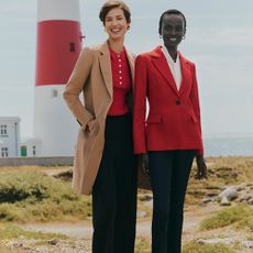 Two models in front of a lighthouse wearind red, black and camel tailored outfits sold at hobbs