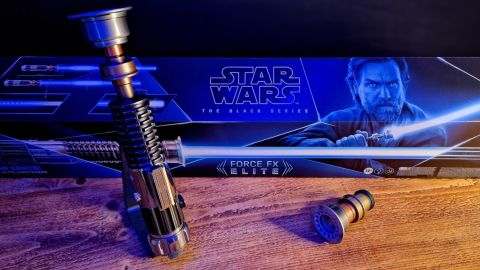 Star Wars The Black Series Obi-Wan Kenobi Force FX Elite Lightsaber on a stand, with an alternate emitter and the box on a wooden table