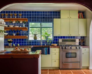 kitchen with light green cabinets, dark blue wall tiles