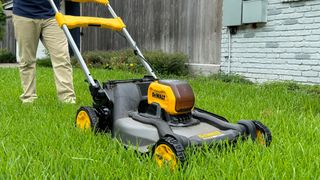 The DeWalt DCMWSP650Y2 being pushed across the grass