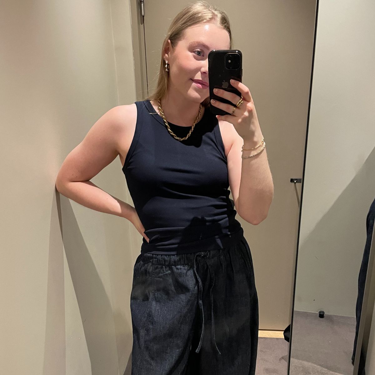 Woman wears navy tank top and denim wide leg trousers
