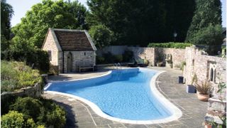 swimming pool with outbuildings and paved surround