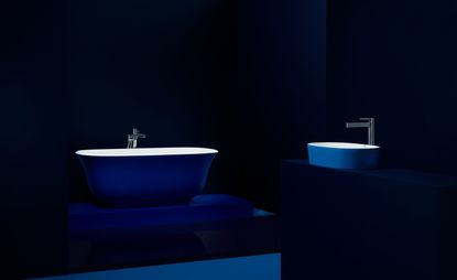 A dark bathroom with a Victoria + Albert bath and sink in Wavelengths blue with chrome fixtures.