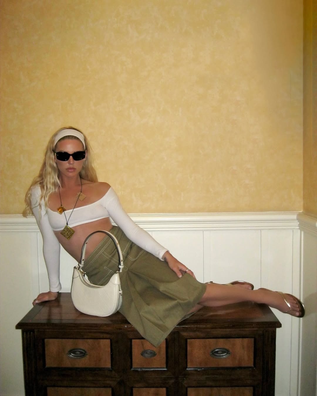 Woman posing on a desk wearing her hair in a thick fabric headband.