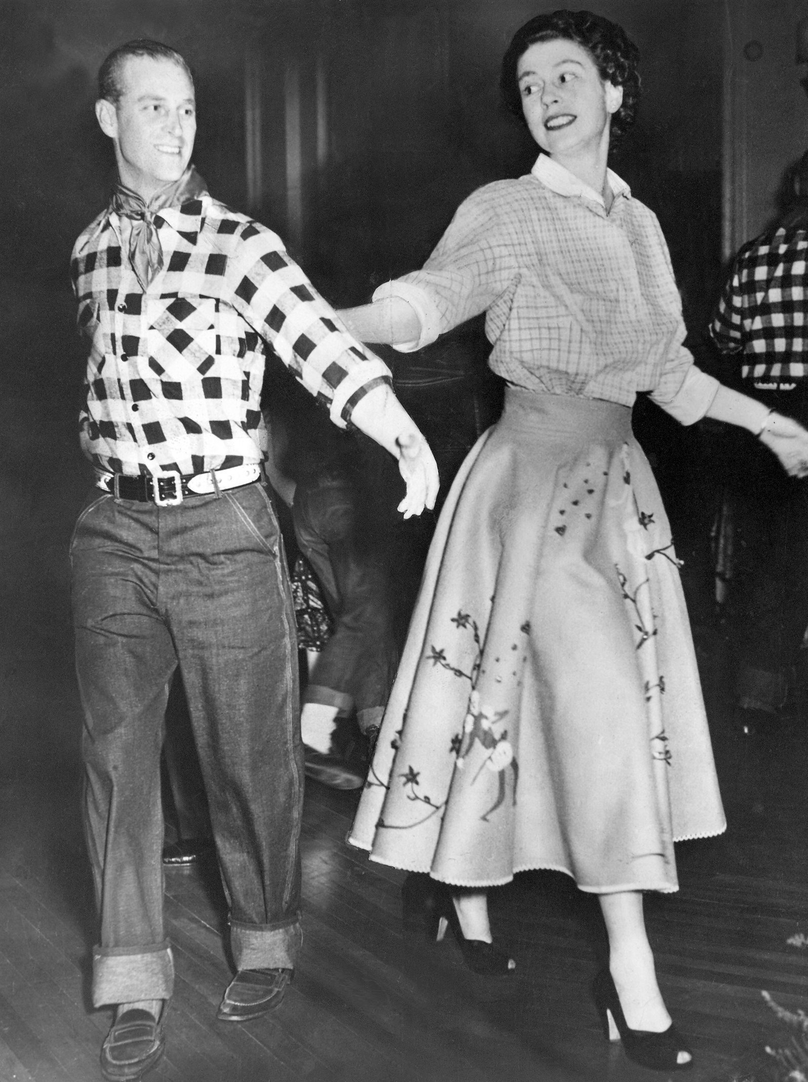 Princess Elizabeth in a poodle skirt and checked shirt dancing with Prince Philip, dressed in jeans and a plaid shirt, in 1951