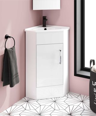 Corner basin unit in small bathroom with pink walls and grey towel