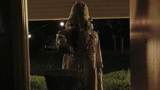 Creepy ghost woman holding basket in doorway in V/H/S/Halloween
