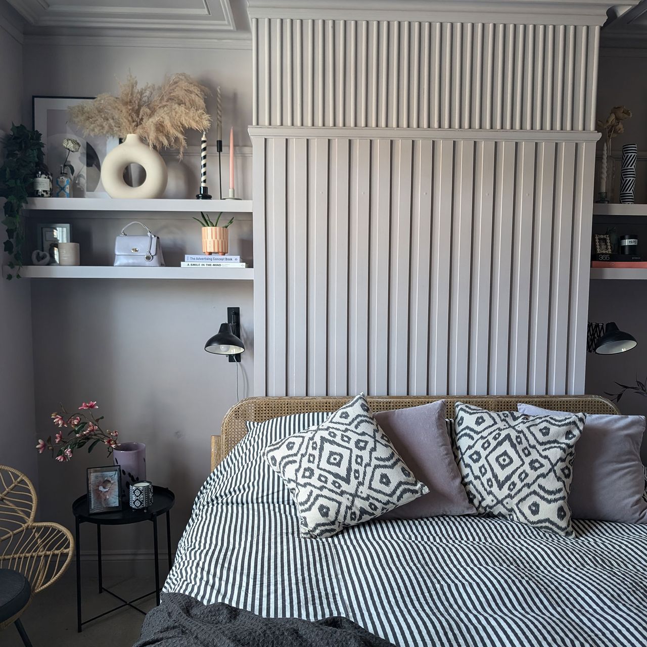 Grey bedroom with wall panelling, floating shelves and monochrome striped bedding