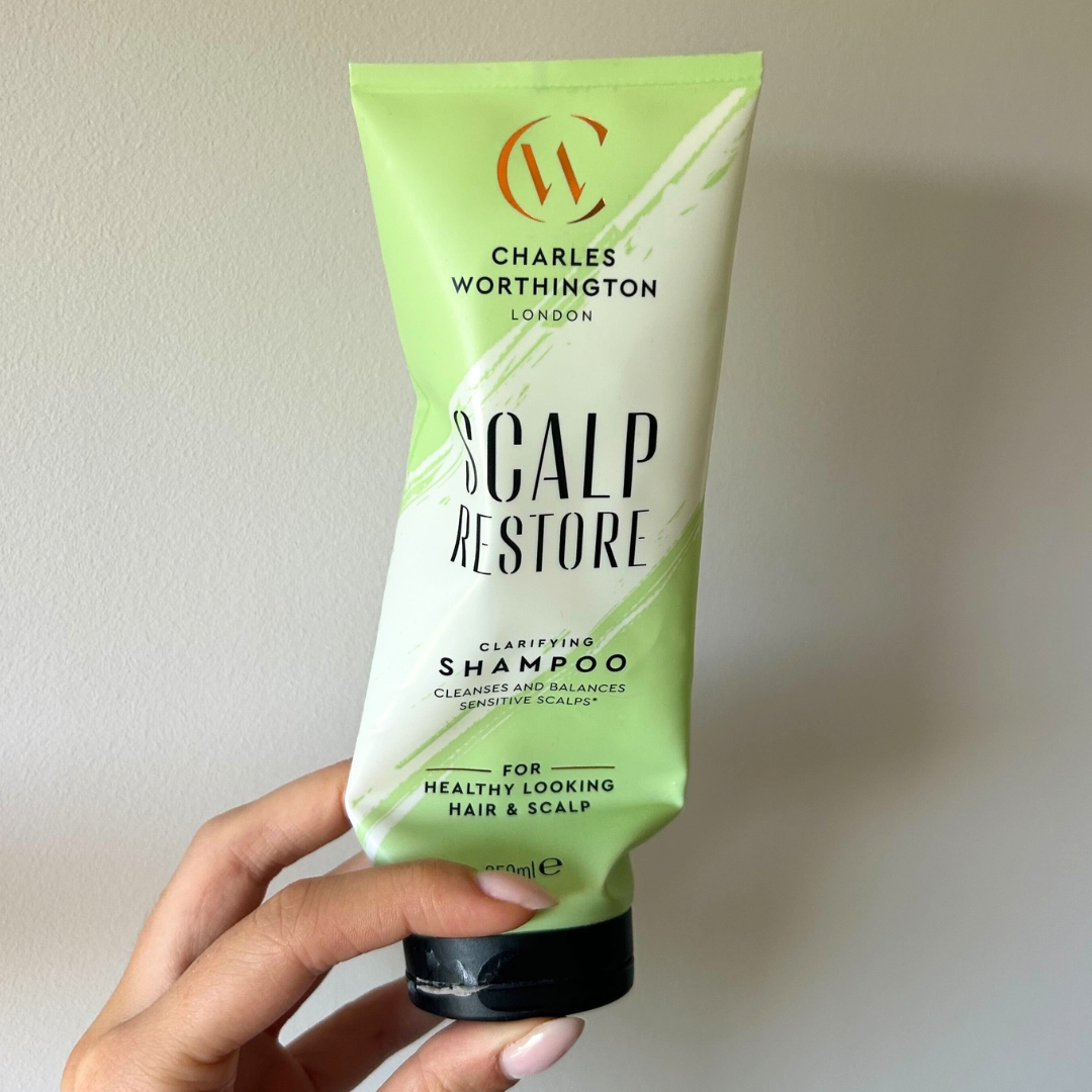 Hand holding empty tube of Charles Worthington Scalp Restore Clarifying Shampoo