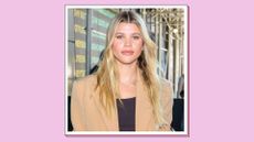 Sofia Richie pictured wearing a camel coat and black top while arriving at the 'Michael Kors' Fashion Show on September 14, 2022 in New York City./ in a pink template