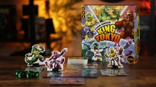 King of Tokyo box, standees, and dice on a wooden table against an orange, out-of-focus background