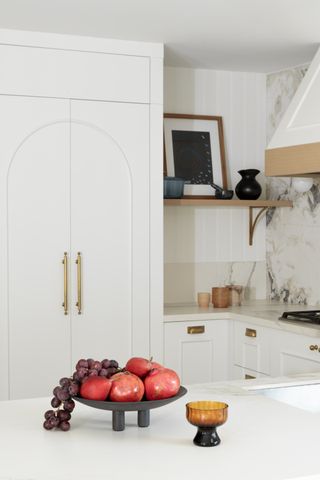 a white kitchen with an arched molding on the door front