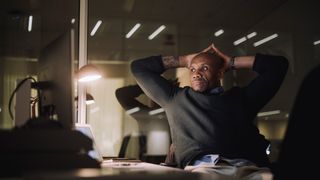 Mature businessman with hands behind head working late in office at night