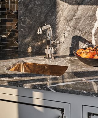 Shiny brass sink in a marble kitchen