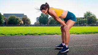 Runner rests with hands on her knees