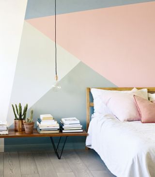 Geometric wall pattern in pink, grey, blue and white by Fired Earth in a white, wooden neutral bedroom
