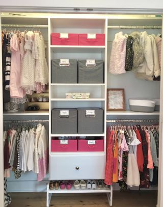 An organised closet for a child including labelled baskets, hanging rails with coats, dresses, and tops grouped together