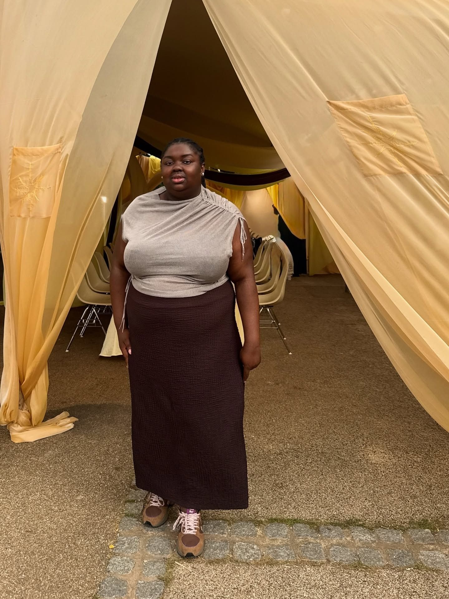 Influencer Abi wears a brown skirt with a beige rouched shoulder top and sneakers.
