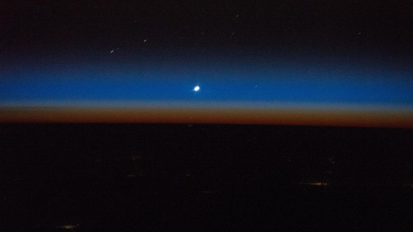 A photograph of Venus as a small dot against the sunset in space