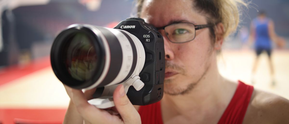 Photographer James Artaius holding the Canon EOS R1 in front of a basketball game