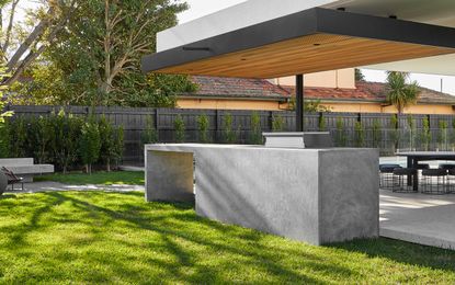 a modern concrete grill island in a backyard