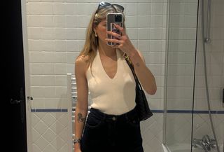 Eliza Huber wearing a cream-colored Zara halter top with dark-wash denim shorts and a brown Bottega Veneta Andiamo bag in a mirror selfie.