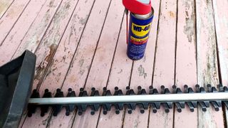 HEdge trimmer blade and WD-40 on rustic pink wooden table
