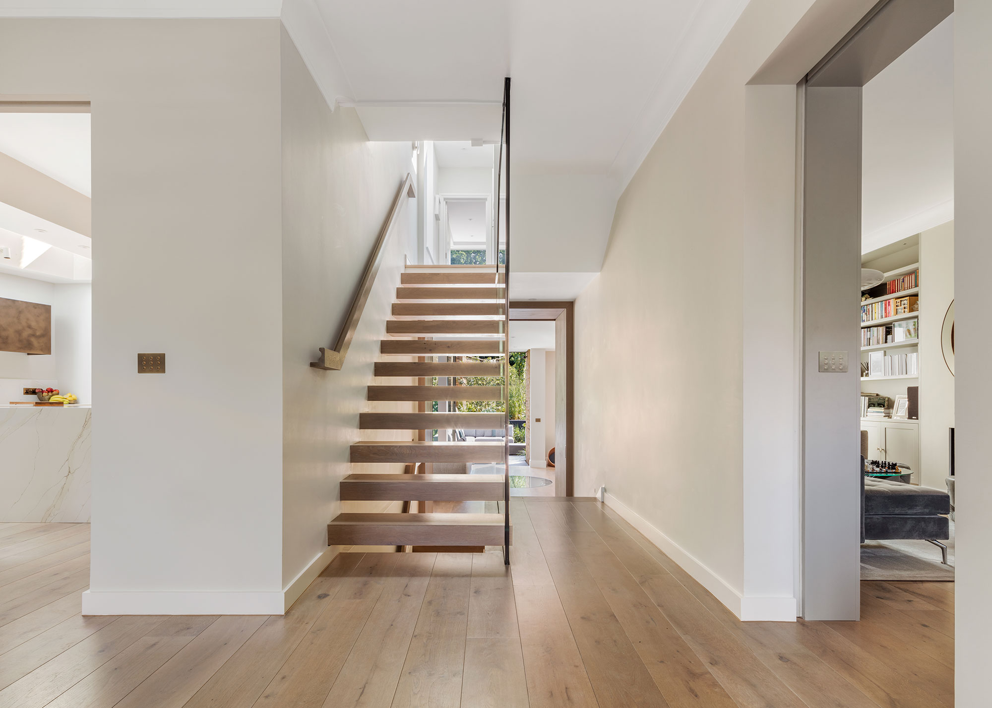 open plan hallway with modern floating open tread staircase and wooden flooring
