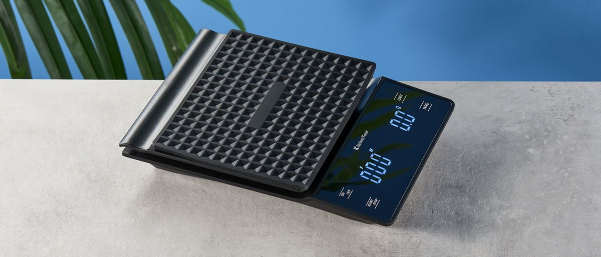 the KitchenTour black coffee scale with a digital LED screen and 0.1g weight accuracy is photographed against a blue background