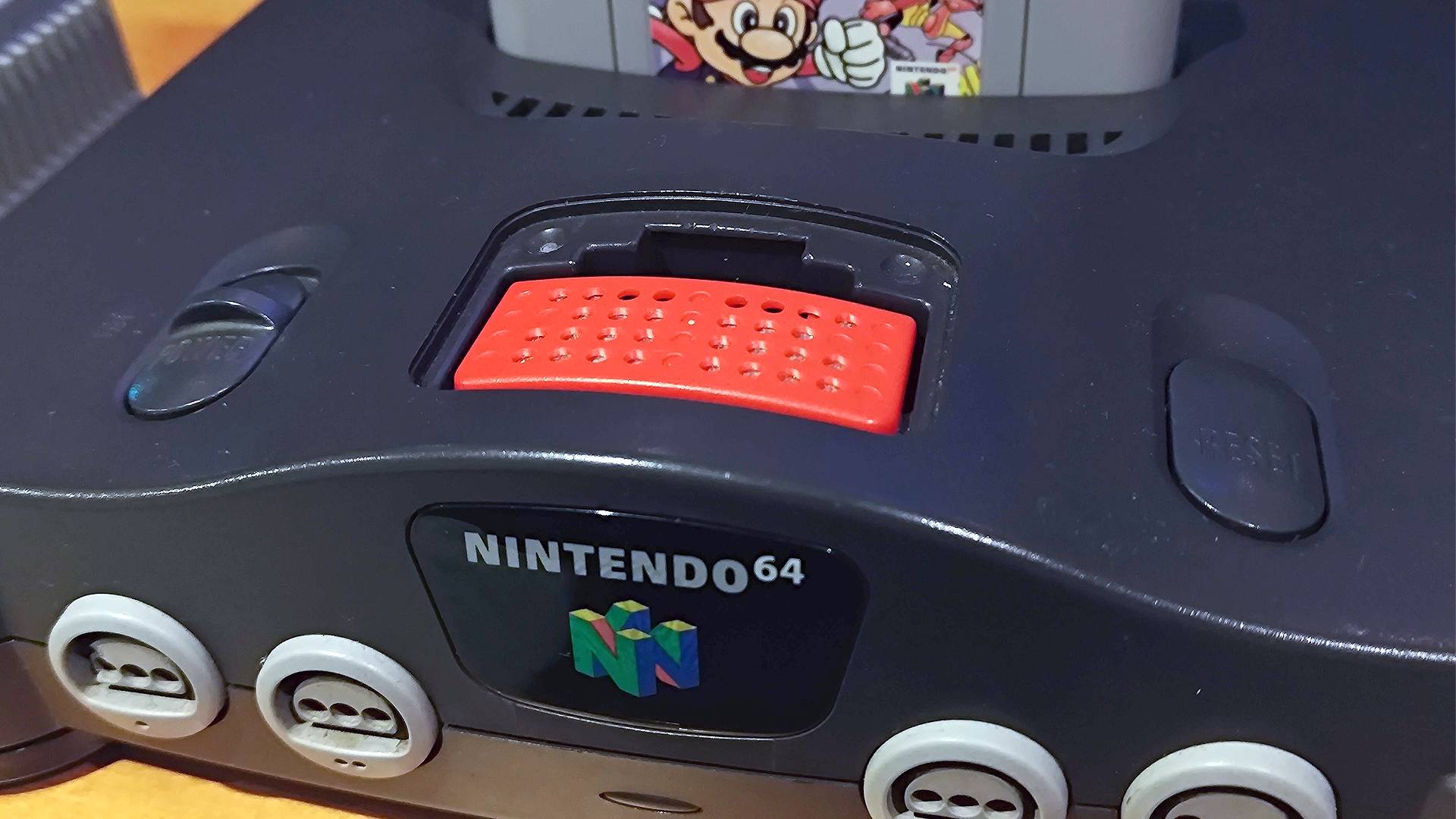 N64 with front cover removed and red Expansion Pak installed.