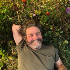 Zach Galifianakis lies smiling in the grass for his Netflix series This Is Gardening