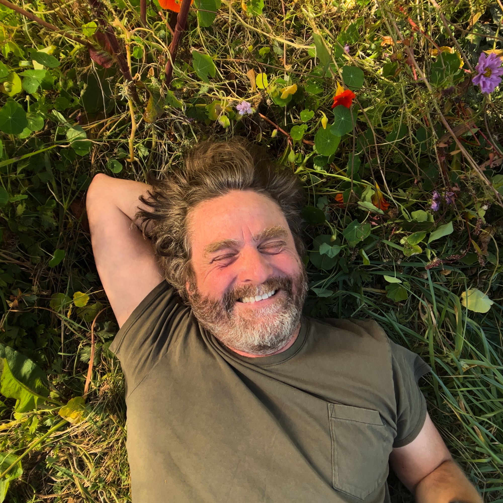 Zach Galifianakis lies smiling in the grass for his Netflix series This Is Gardening