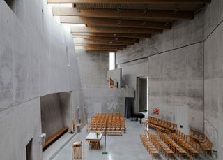 Maria Magdalena Church / Double Church For Two Faiths by KSG Architekten. A large concrete room with many wooden chairs facing a podium.