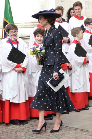 Catherine, Princess of Wales with a bouquet of flowers, speaks to members of the choir as she departs the 2023 Commonwealth Day Service at Westminster Abbey on March 13, 2023 in London, England.