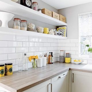 kitchen room with white wall and white tiles with wooden worktop