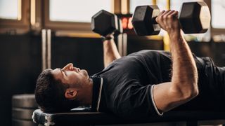 a photo of a man doing a dumbbell bench press