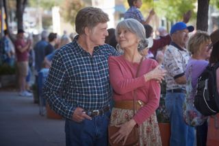 robert redford wears a blue plaid shirt and jane fonda wears a pink longsleeved shirt as they walk down the street together in the movie our souls at night