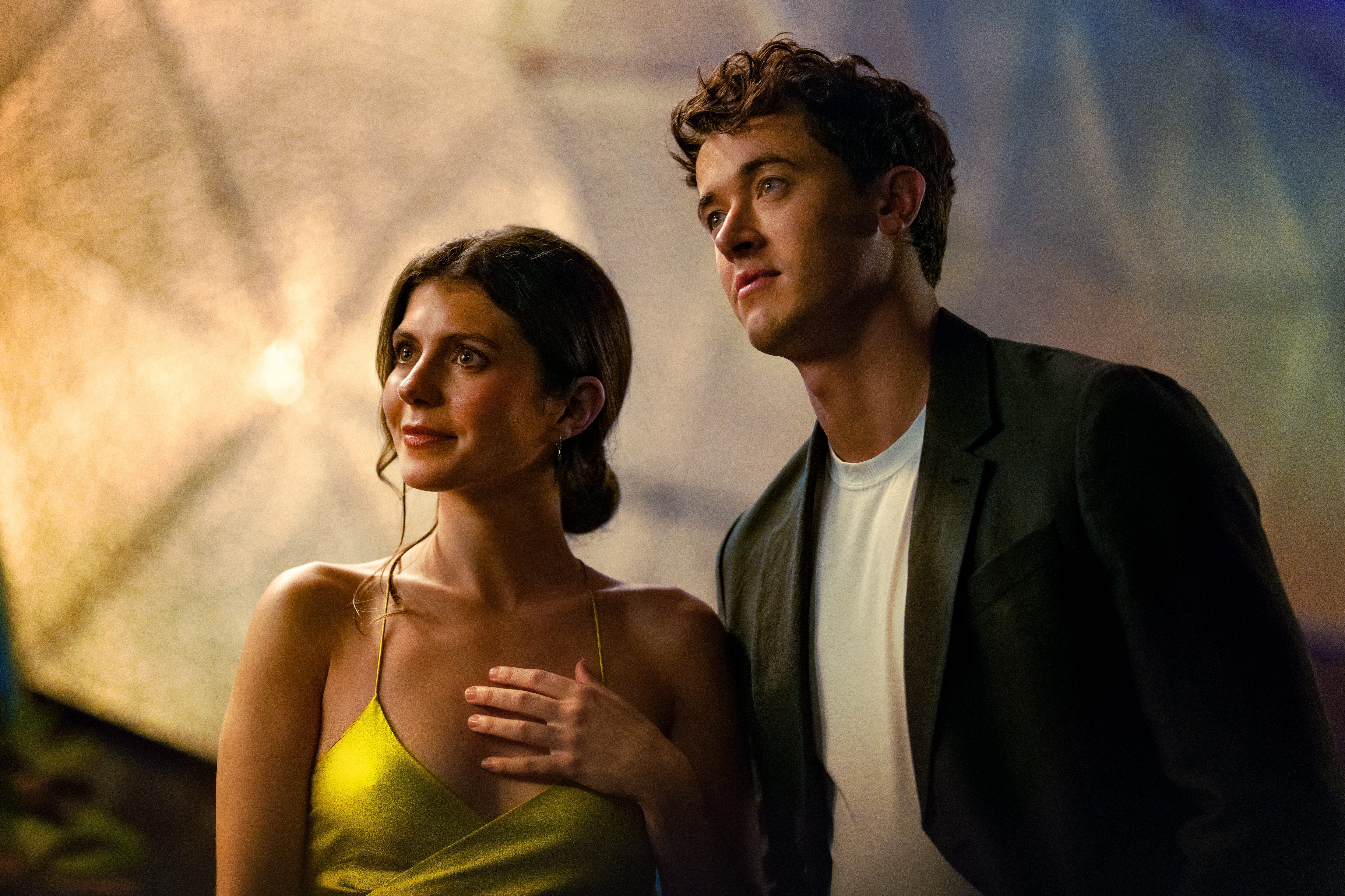 Emily Bader as Poppy wearing a bright yellow dress and Tom Blyth as Alex wearing a sports coat and white t-shirt in People We Meet on Vacation