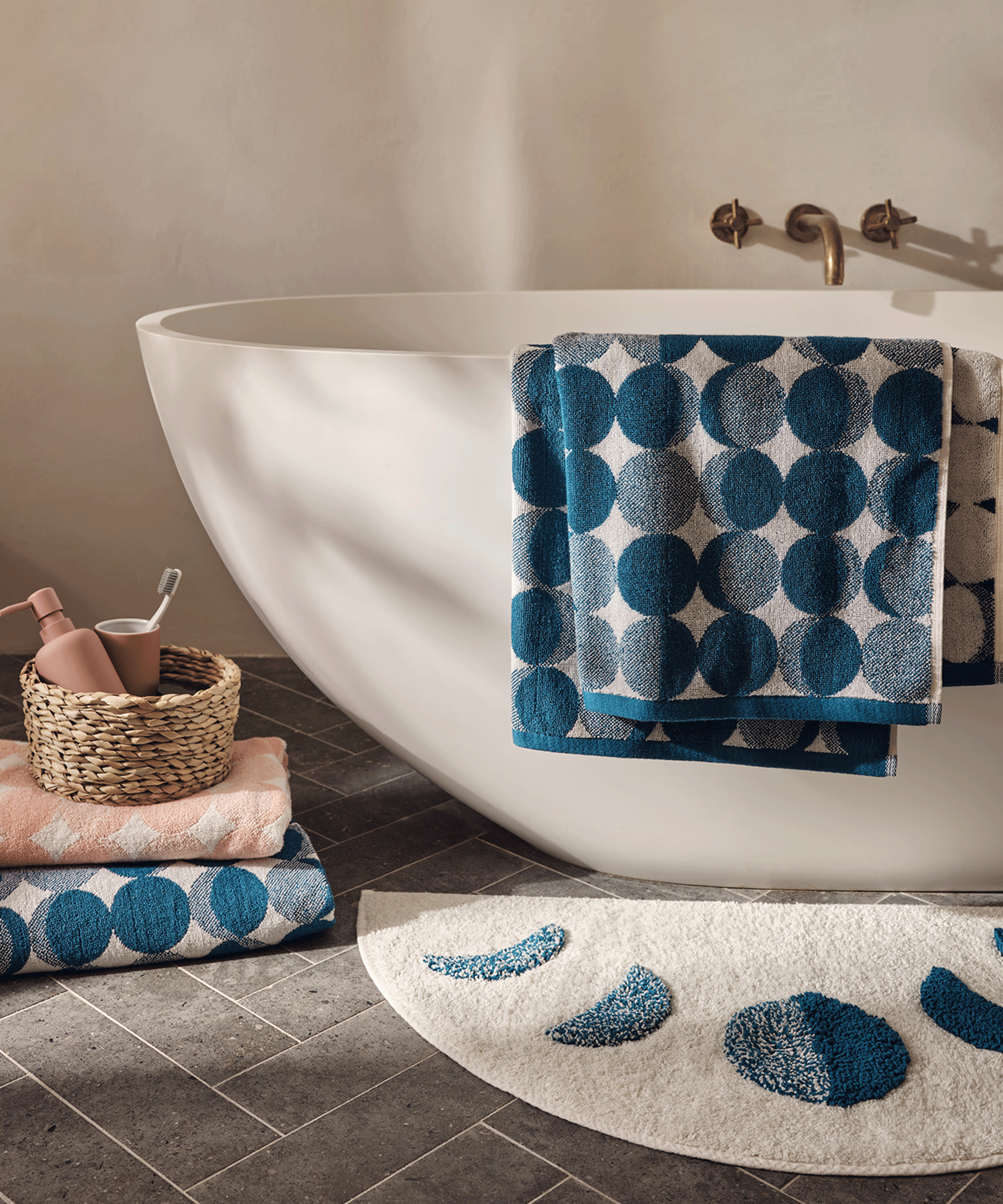 A small neutral bathroom with a small bathtub and moon themed toweled accessories