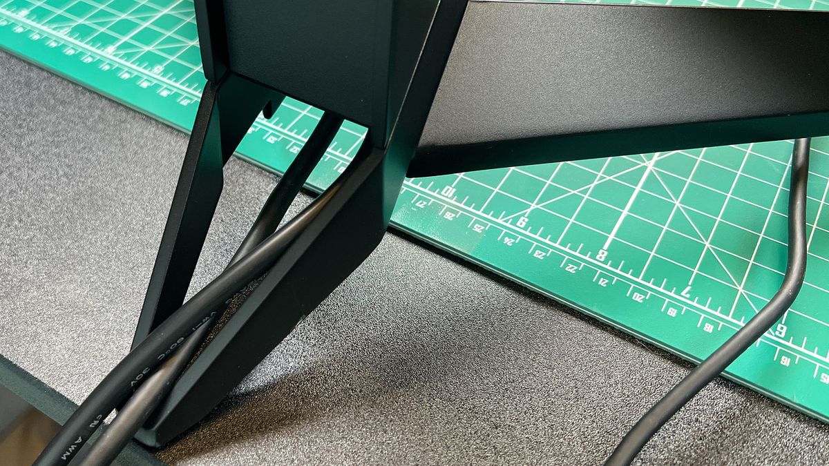 An AOC Agon Pro AG274QZM on a black desk with a green deskmat underneath