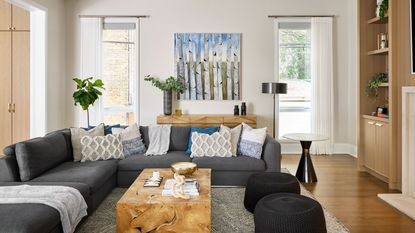 Grey sectional dressed with textured cushions in cozy living room with contemporary art on the wall and feature wooden coffee table