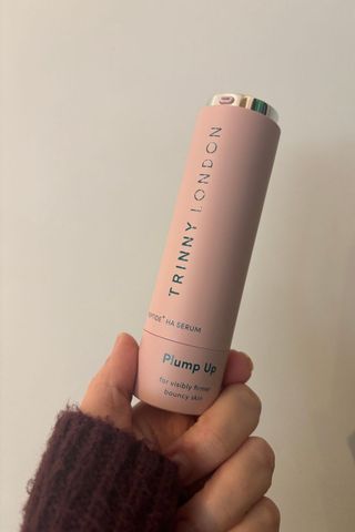 a hand holding trinny london plump it serum