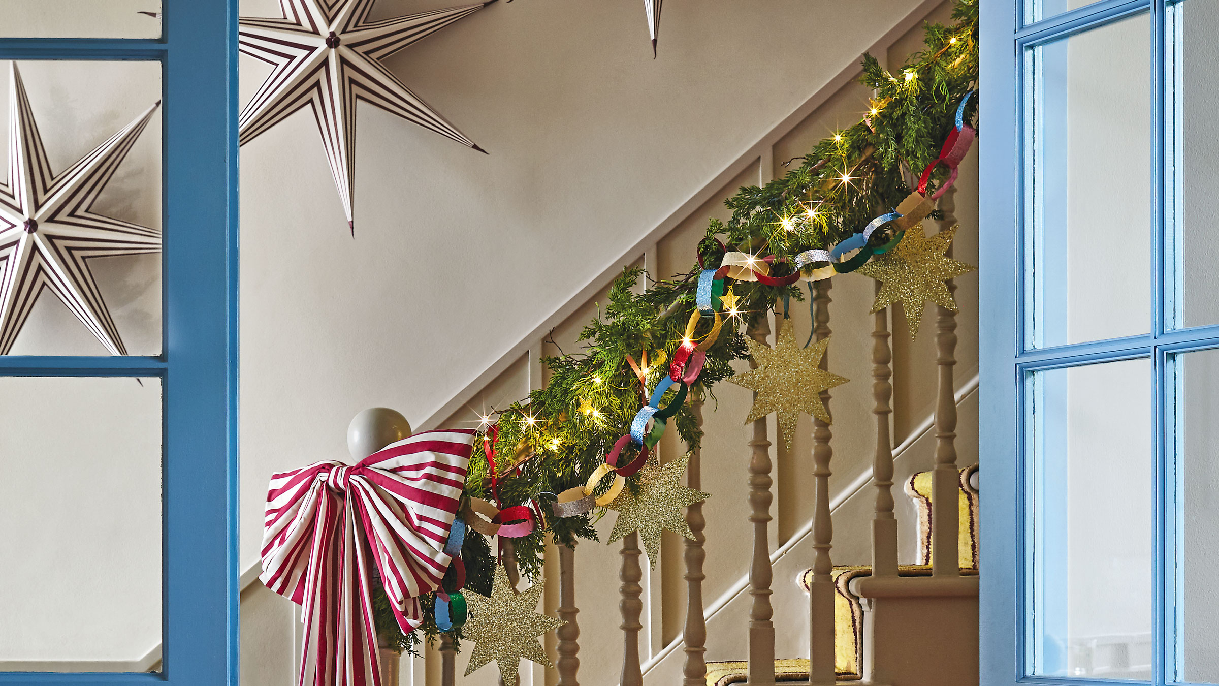 White staircase with blue glass doors and green stars with a red bow at the bottom