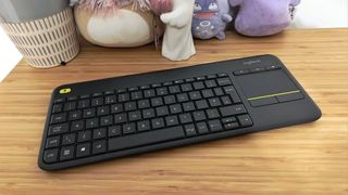 Logitech K400 Plus keyboard sitting on woodgrain surface