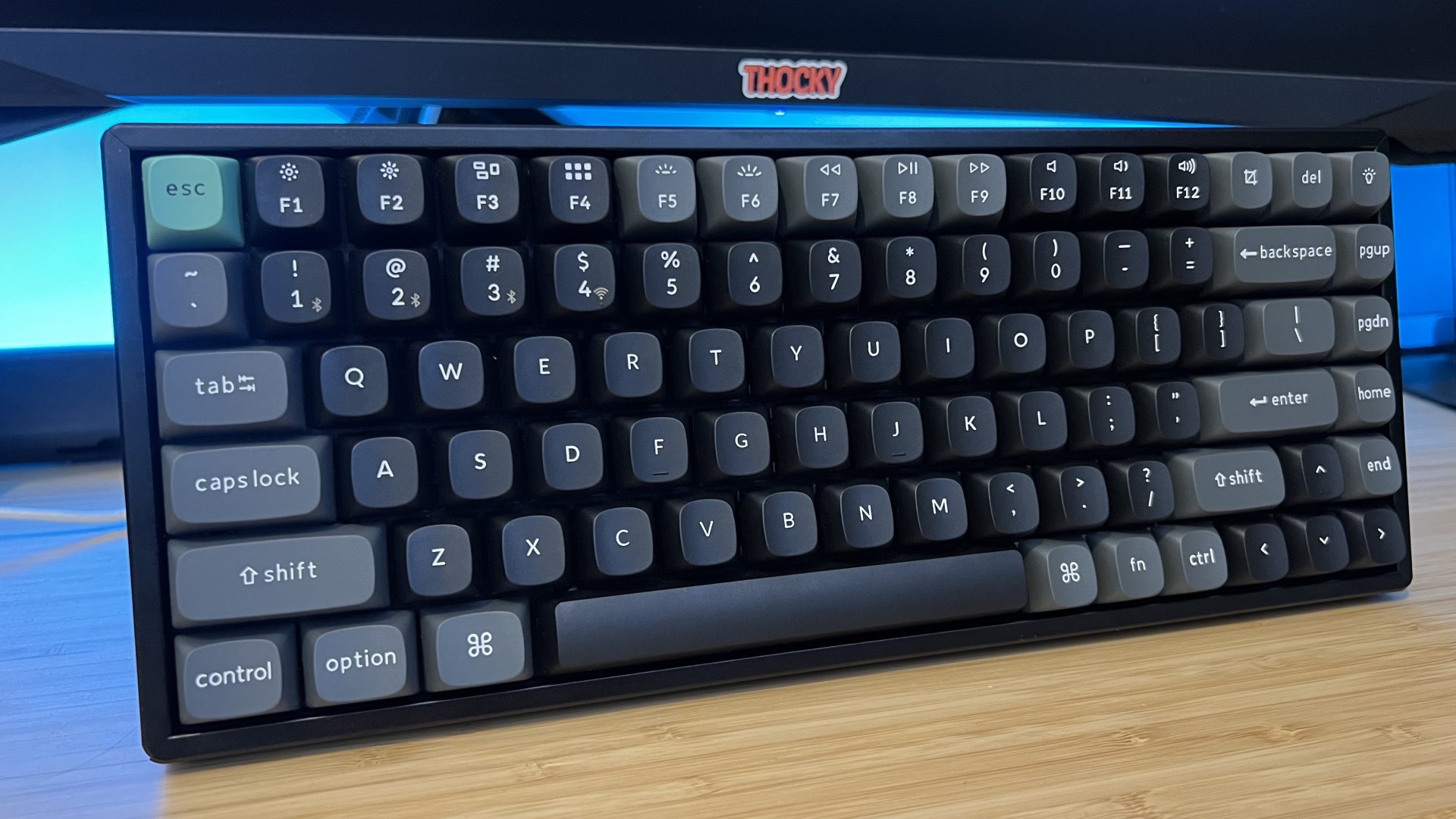 Keychron K2 Ultra 8K gaming keyboard on a wooden desk with blue backlighting