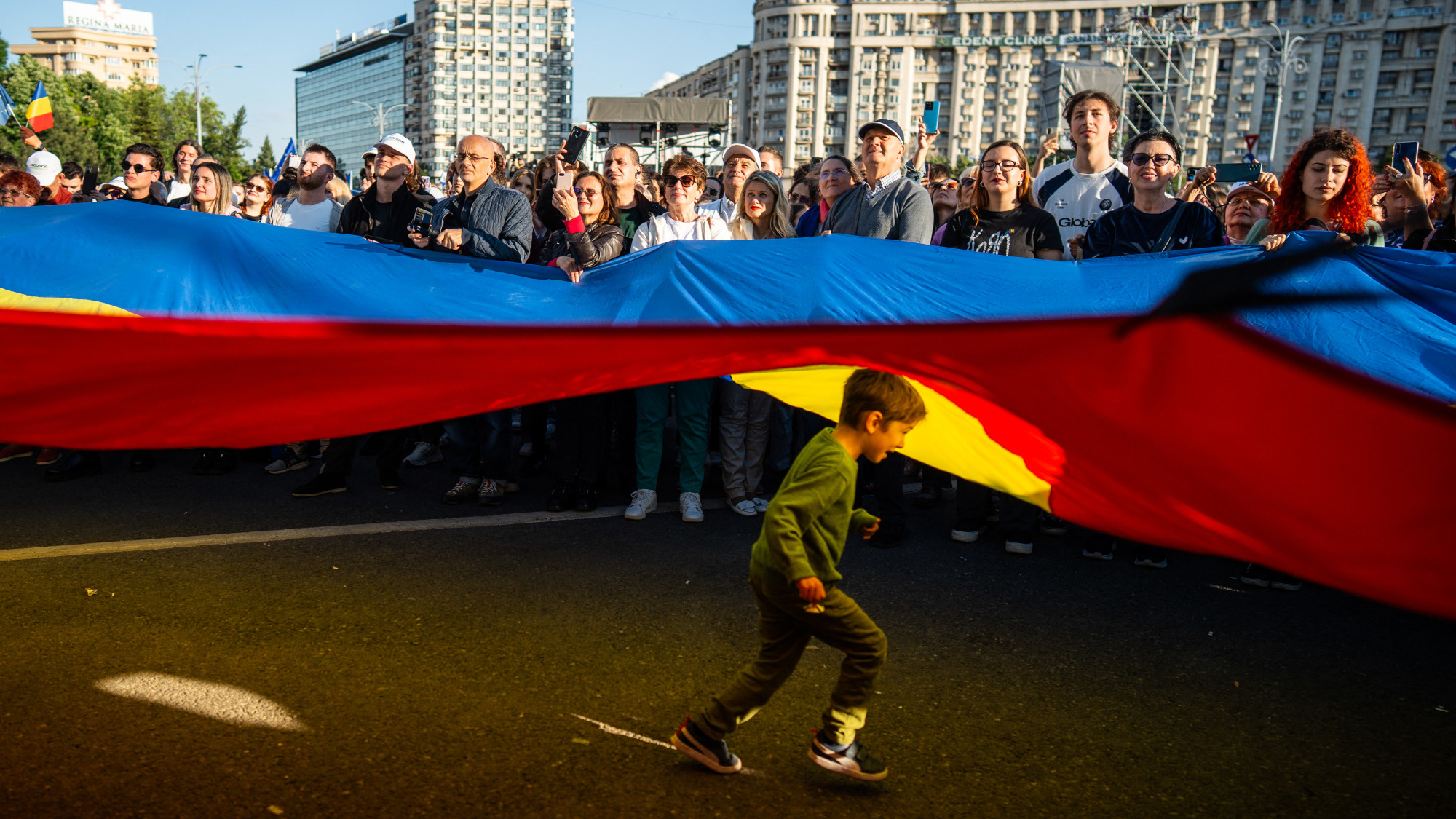 A child runs under a large flag